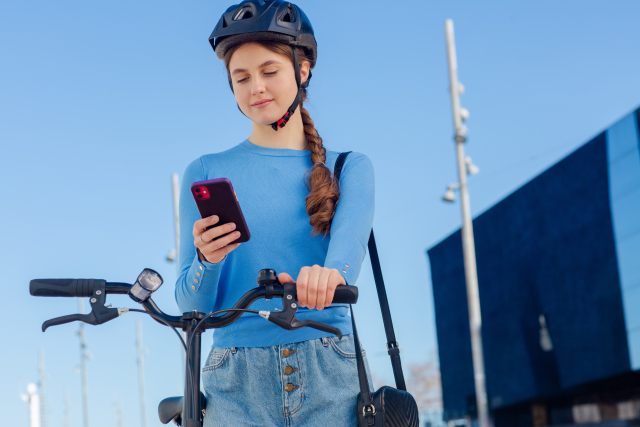 自転車を止めてスマホを操作している女性